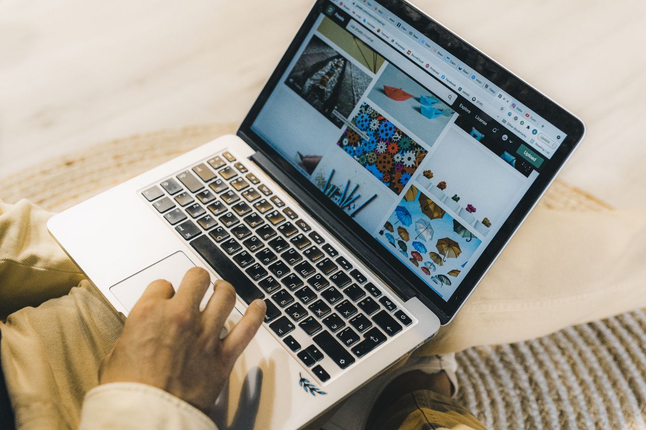Une personne utilisant un ordinateur portable pour parcourir des sites de photos de stock. Travail indépendant dans un cadre chaleureux.